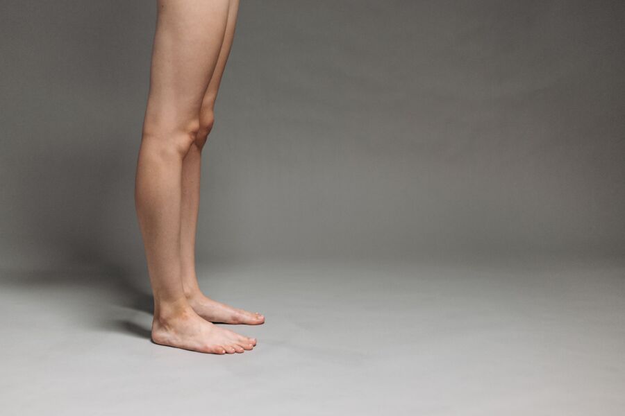 Foto de estudio de piernas desnudas contra un telón de fondo gris, centrado en el diseño minimalista.