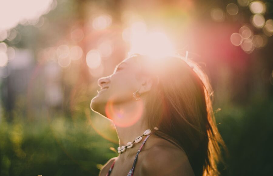Una mujer tomando el sol con una sonrisa vibrante y un estado de ánimo despreocupado al aire libre.