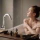 Una serena escena de baño con una mujer disfrutando de la relajación con incienso y una taza de té caliente.