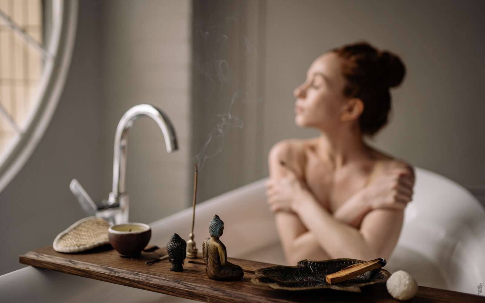 Una serena escena de baño con una mujer disfrutando de la relajación con incienso y una taza de té caliente.