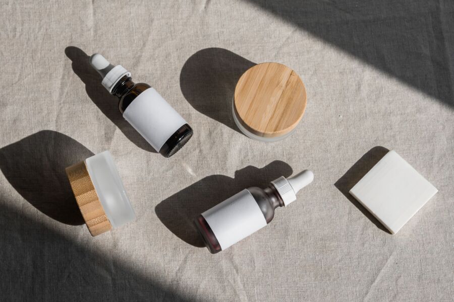 Una disposición plana minimalista de botellas y frascos de cosméticos sobre un paño de lino, perfecta para presentaciones de productos de belleza.
