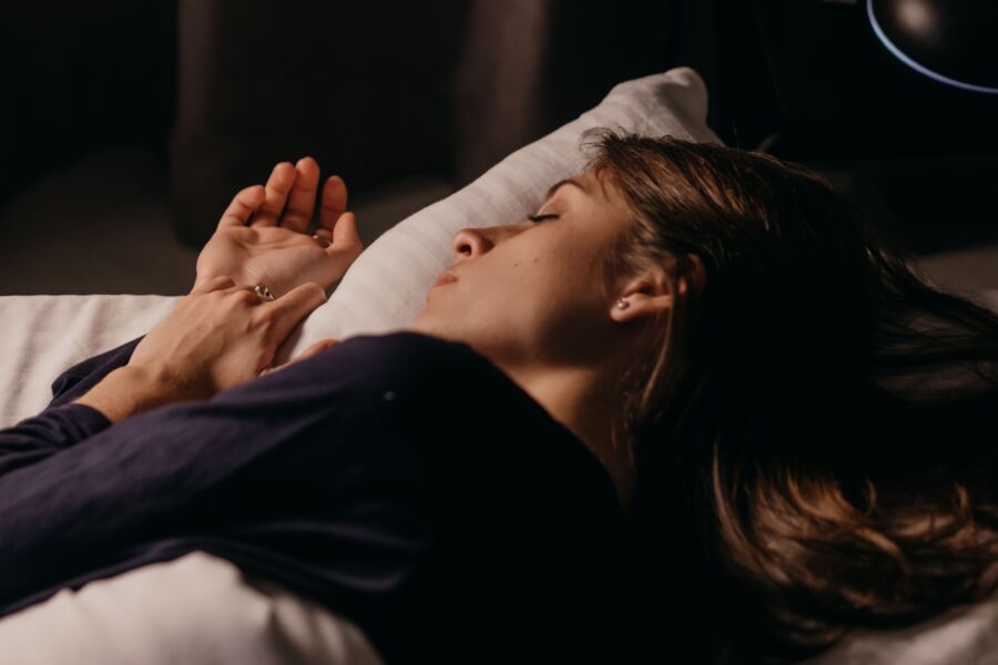 Una mujer durmiendo cómodamente sobre una almohada en un dormitorio suavemente iluminado, capturando un ambiente nocturno tranquilo.