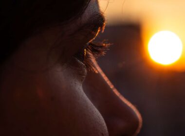 Un primer plano cautivador del ojo de una persona con una puesta de sol vibrante en el fondo, creando un ambiente cálido e introspectivo.