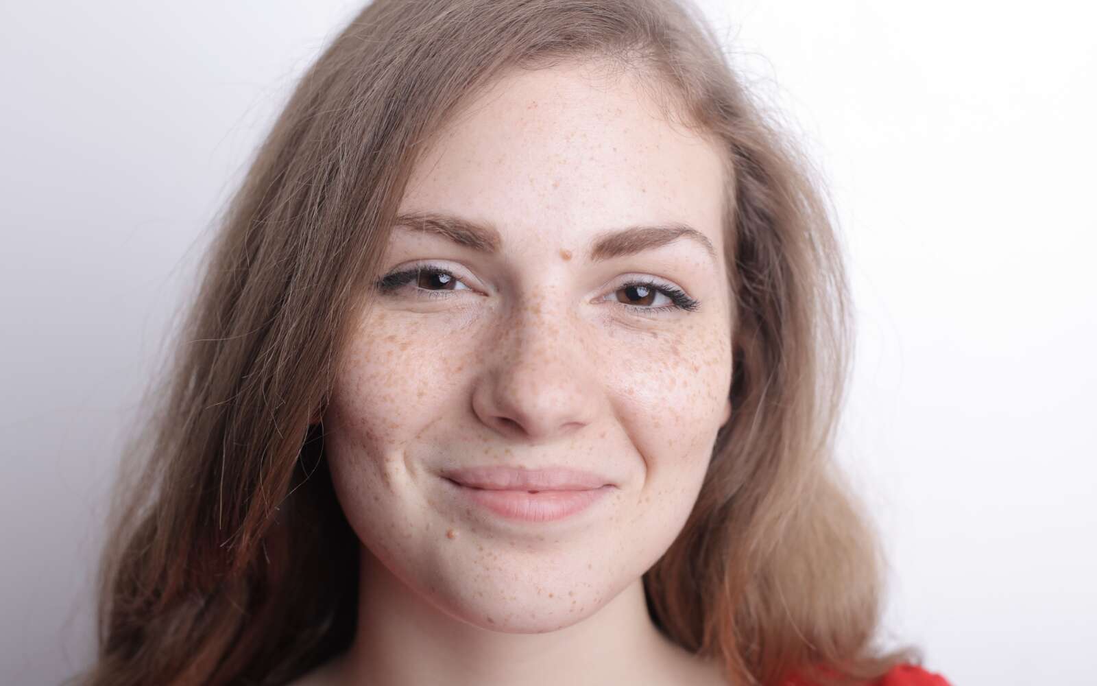 Retrato en primer plano de una joven sonriente con pecas y belleza natural.