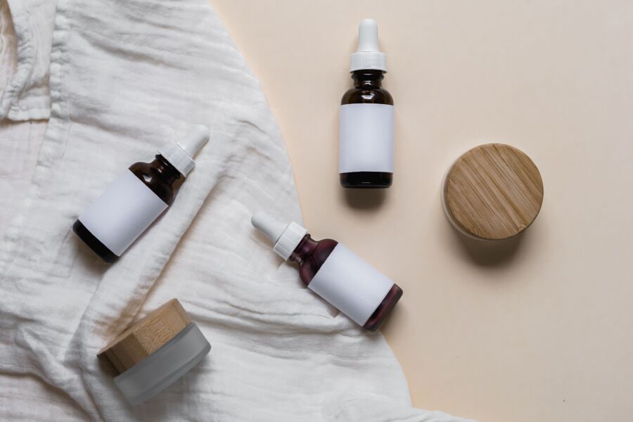 Elegantes botellas de vidrio para el cuidado de la piel con etiquetas en un tejido texturizado, perfectas para la marca cosmética y la exhibición de productos.