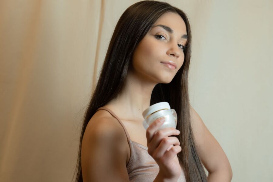 Hermosa mujer mostrando un producto para el cuidado de la piel en una pose elegante.