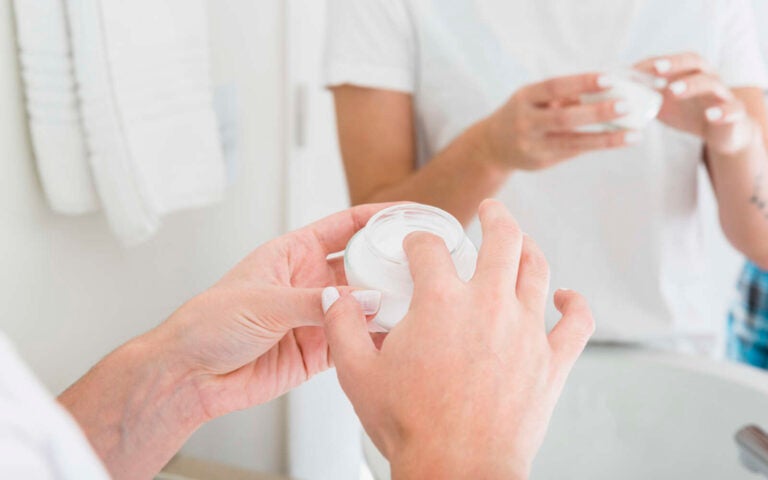 Primer plano de la mano de la mujer que aplica la crema hidratante